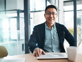 Mann sitzt mit Tablet und seinem Kaffee an einem Tisch