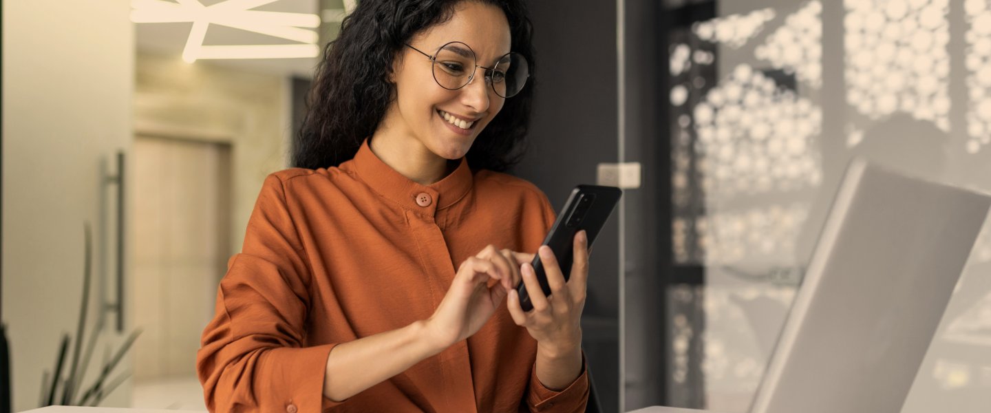 young woman with smartphone in front of a laptop