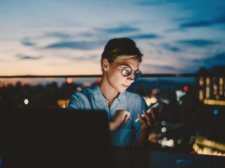 woman looking at her phone with skyline in the background